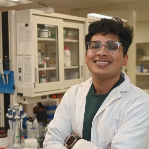 A Scientist wears a white lab coat in a lab environment